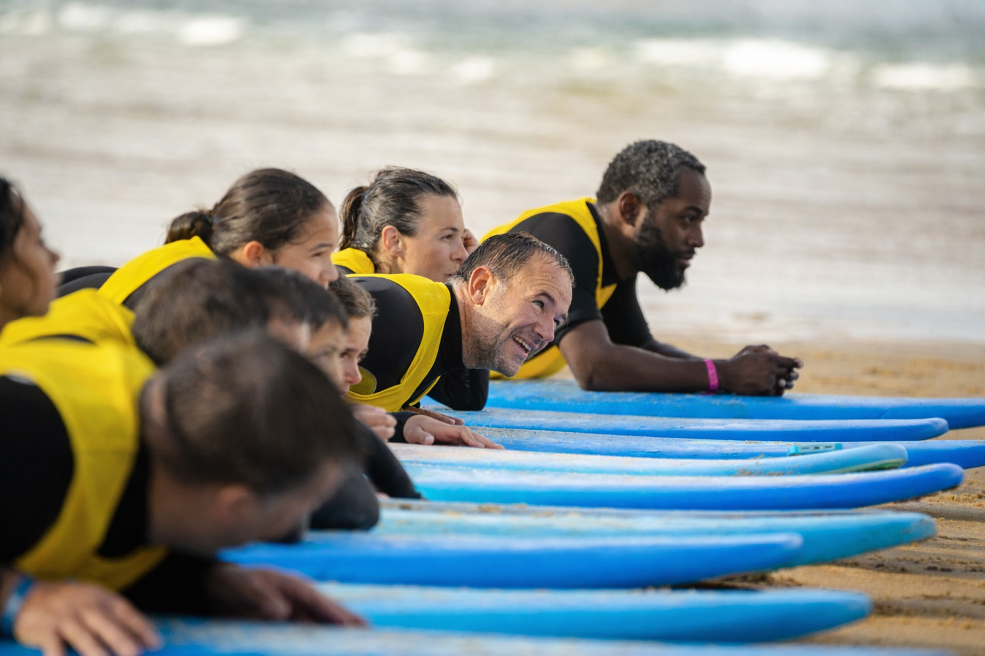 Groupe de participants accompagné pendant un cours de surf