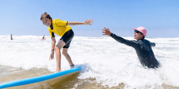 Surfeur débutant accompagné par un moniteur pendant un cours de surf