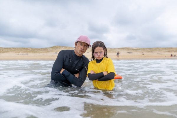 Moniteur de surf aux côtés d’une jeune surfeuse dans l’océan
